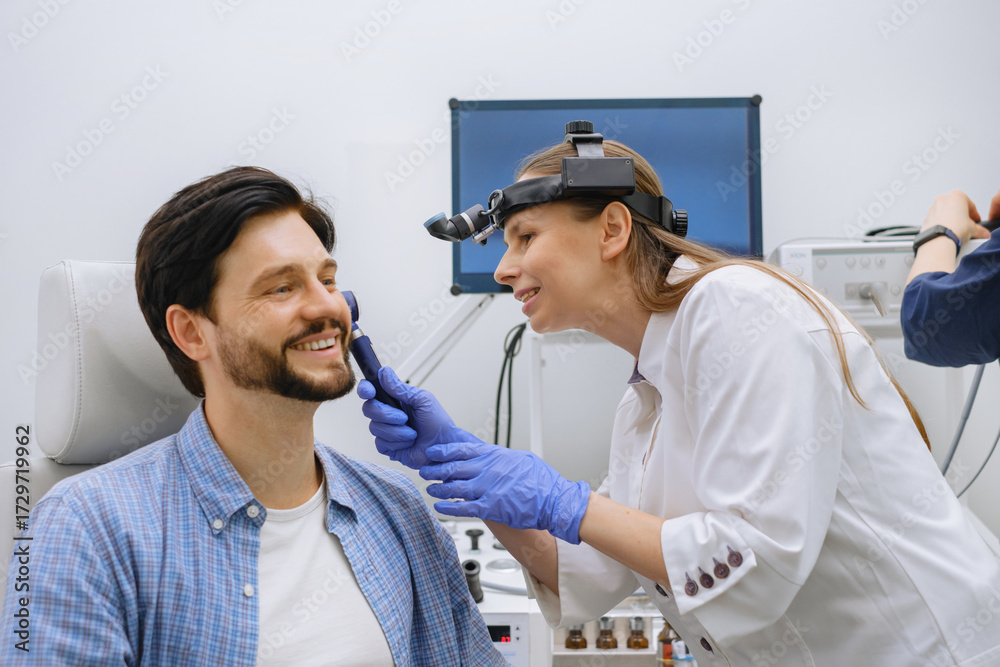ENT doctor examining male patient with otoscope in modern clinic ...