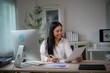 © PaeGAG - Asian businesswoman smiling while working with paperwork