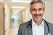 © Blithe - Smiling male doctor in a hospital corridor wearing a stethoscope and suit