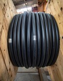 Large coil of black cable wound tightly on a wooden spool