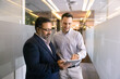 © fizkes - Indian and Latino colleagues standing in office hallway with tablet