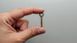 © THESUN - Human hand holding small vintage key, simple metal object representing secret solution to unlock potential