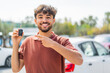 © luismolinero - Young Arabian handsome man holding car key at outdoors and pointing it