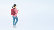 © metamorworks - A full-body photo of a teenage woman walking with a smartphone. (We also sell PNGs that are cropped and have transparent background. Please search for 'PNG' from the creator link.)
