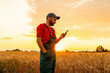 © Barillo_Images - Agricultural worker using mobile phone in crop field during summer evening