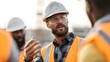 © Thares2020 - A construction foreman gestures while discussing plans with a team of workers on an outdoor job site
