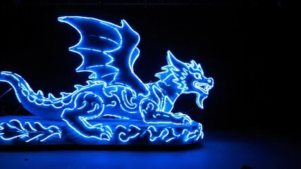 Wall Mural - Glowing Neon Dragon Outline - A neon parade float of a dragon with a blue outline is displayed against a black background. The float features intricate designs and vibrant glowing lights.