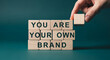 © Mirivox - Wooden blocks spelling 'You are your own brand',  a hand placing the final block.  Represents personal branding and self-marketing concepts