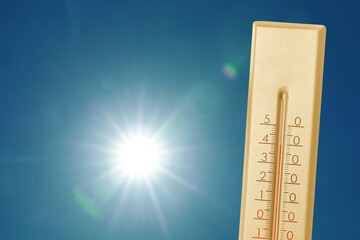 Wall Mural - thermometer showing high temperature against sky with bright sun. extremely hot weather