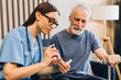 © Maria Vitkovska - Nurse checking senior man's blood sugar level at home