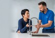 © Alze31 - Plumber explaining faucet repair to a homeowner in a bright kitchen, providing expert advice and friendly service for a common household issue.
