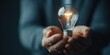 © rudy - Illuminated light bulb held in hands symbolizing idea and innovation