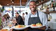 © mila103 - A waiter smiles as he carries two plates filled with pasta and garnished dishes in a lively restaurant. Diners enjoy their meals in the background creating a warm and bustling environment.