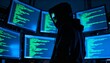 © igor.nazlo - Hacker silhouette in dark hoodie in front of multiple computer screens with code, cyber attack concept