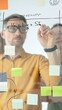 © volha_r - Business team collaborating on a project, using a glass board with sticky notes and marker to brainstorm ideas and develop a strategic plan in office space