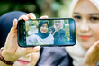 © Mang Kelin - Two beautiful sibling Asian women taking a selfie together in the park.
