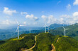 © ABCDstock - Aerial view of wind turbines on the green mountain generating clean and renewable energy on a sunny day