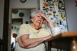 © Halfpoint - Portrait of worried senior woman sitting in kitchen.