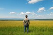 © YouraPechkin - Man standing in a golden field gazing at the vast landscape under a blue sky