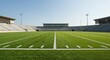 © Ari - Wide, symmetrical view of an empty football stadium field under a clear, bright blue sky.