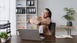 © amnaj - Businesswoman stretching at office desk taking break