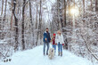 © zinkevych - Parents and their daughter walking with a dog in a snowy forest