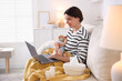 © New Africa - Telehealth. Smiling mother with her baby having online consultation with doctor by laptop on sofa at home