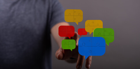 Man pointing to colorful speech bubbles formed from puzzle pieces. It symbolizes communication, networking, collaboration, and problem solving i