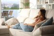 © PheelingsMedia - Woman sitting in a sofa relaxing contemplating through a window