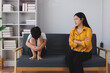 © Phimwilai - Mother ignoring sad child sitting on sofa at home