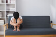 © Phimwilai - Sad child sitting on sofa hugging knees