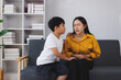 © Phimwilai - Caring child comforting mother experiencing stomach ache on sofa
