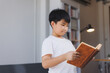 © Phimwilai - Young student reading a book in a library, concentrated learning