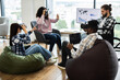 © sofiko14 - Group of diverse adults using virtual reality headsets and laptops in modern office setting. Individuals of various backgrounds collaborating in technology-driven workspace fostering creativity