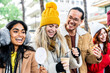 Happy friends having fun drinking mulled wine and hot chocolate at Christmas Market - Cheerful young people enjoying winter holidays on weekend vacation - Tourism lifestyle and friendship concept