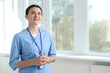 © New Africa - Nurse in uniform near window indoors, space for text