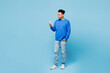 © ViDi Studio - Full body young man of African American ethnicity wear sweatshirt casual clothes hold in hand use mobile cell phone isolated on plain pastel light blue background studio portrait. Lifestyle concept.