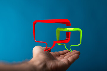 Wall Mural - Hand holding red and green speech bubbles symbolizes modern communication, discussions, and expressing opinions in online spaces and communities