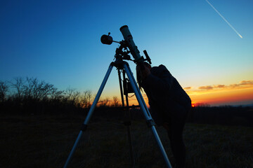 Wall Mural - Amateur astronomer using telescope for watching stars, Moon, planets and other celestial objects from a field in nature.