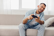 © SHOTPRIME STUDIO - A joyful man playing video games at home, embracing a moment of relaxation and self-care amidst personal challenges and digital distractions.