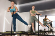 © New Africa - Smiling women training on mini exercise trampolines in fitness studio, low angle view