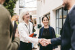 © Maskot - Smiling senior female business expert shaking hand with male colleague at networking event in convention center