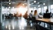 © Thares2020 - Blurred modern office interior with people working at desks and laptops bathed in natural light