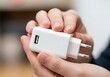 © Malik - Person holding a modern white USB charger, emphasizing its sleek design and connectivity ready for smartphones