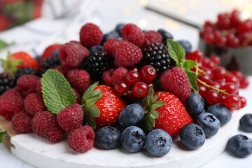 Wall Mural - Different ripe berries and mint leaves on white table, closeup