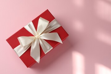 Wall Mural - Beautiful gift box with bow on pink background, top view. Space for text