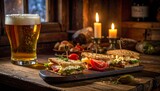 A rustic scene with a beer, appetizers, and lit candles on a wooden surface next to a window. A cozy, inviting atmosphere