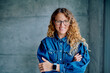 © we.bond.creations - Professional woman with curly hair smiling and crossing arms, expressing confidence and success in modern business