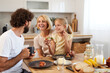 © Stockphotodirectors - Family members gather around the kitchen table, sharing joyful moments and breakfast. The atmosphere is warm and inviting, filled with laughter and tasty meals.
