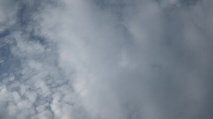 Wall Mural - Looking up into a blue sky at white and gray clouds moving rapidly in a time lapse. The clouds close in to fill the sky. Sky only in the clip.
